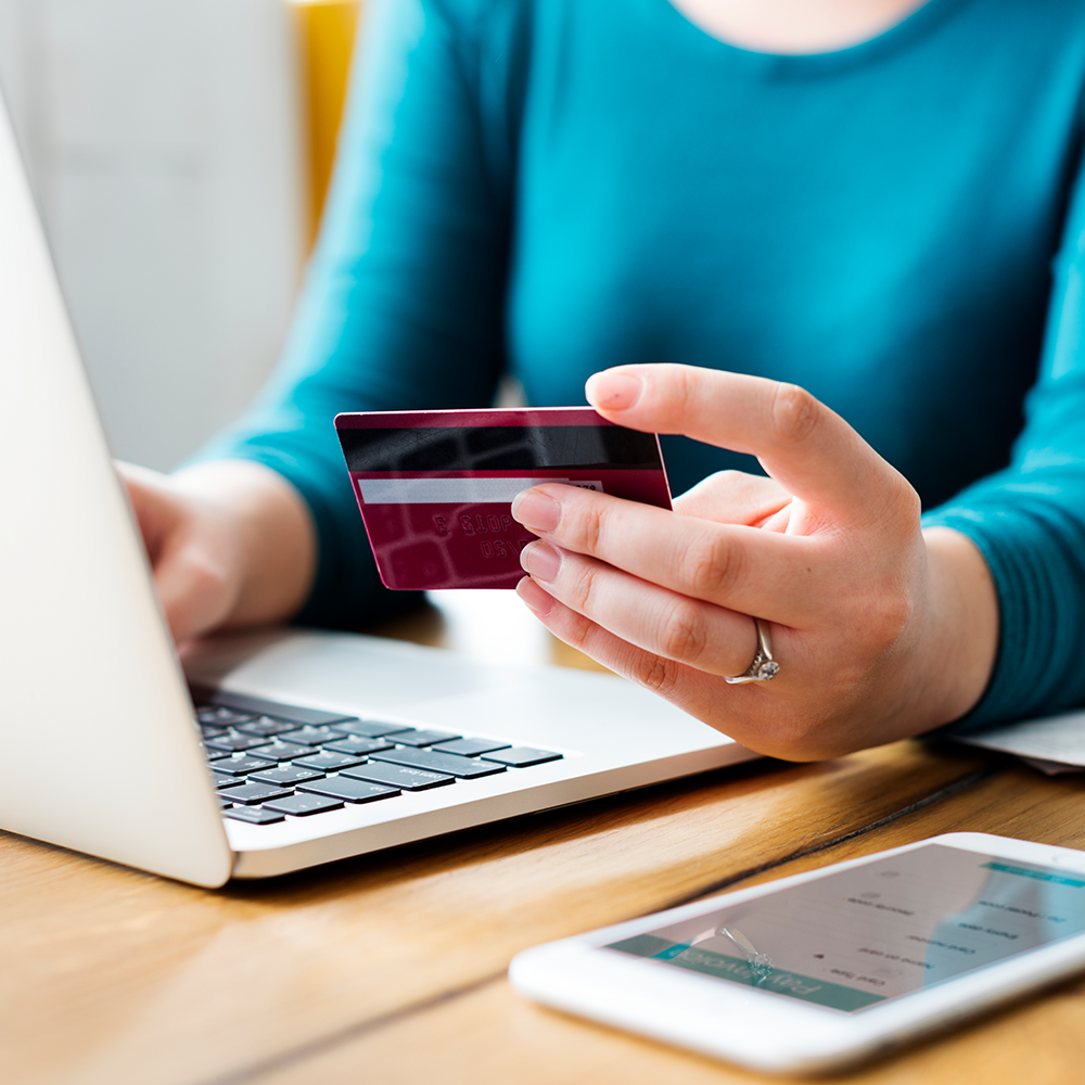 Woman in blue shirt holding credit card.